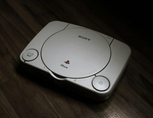 Foto do console PlayStation 1 em um chão de madeira.